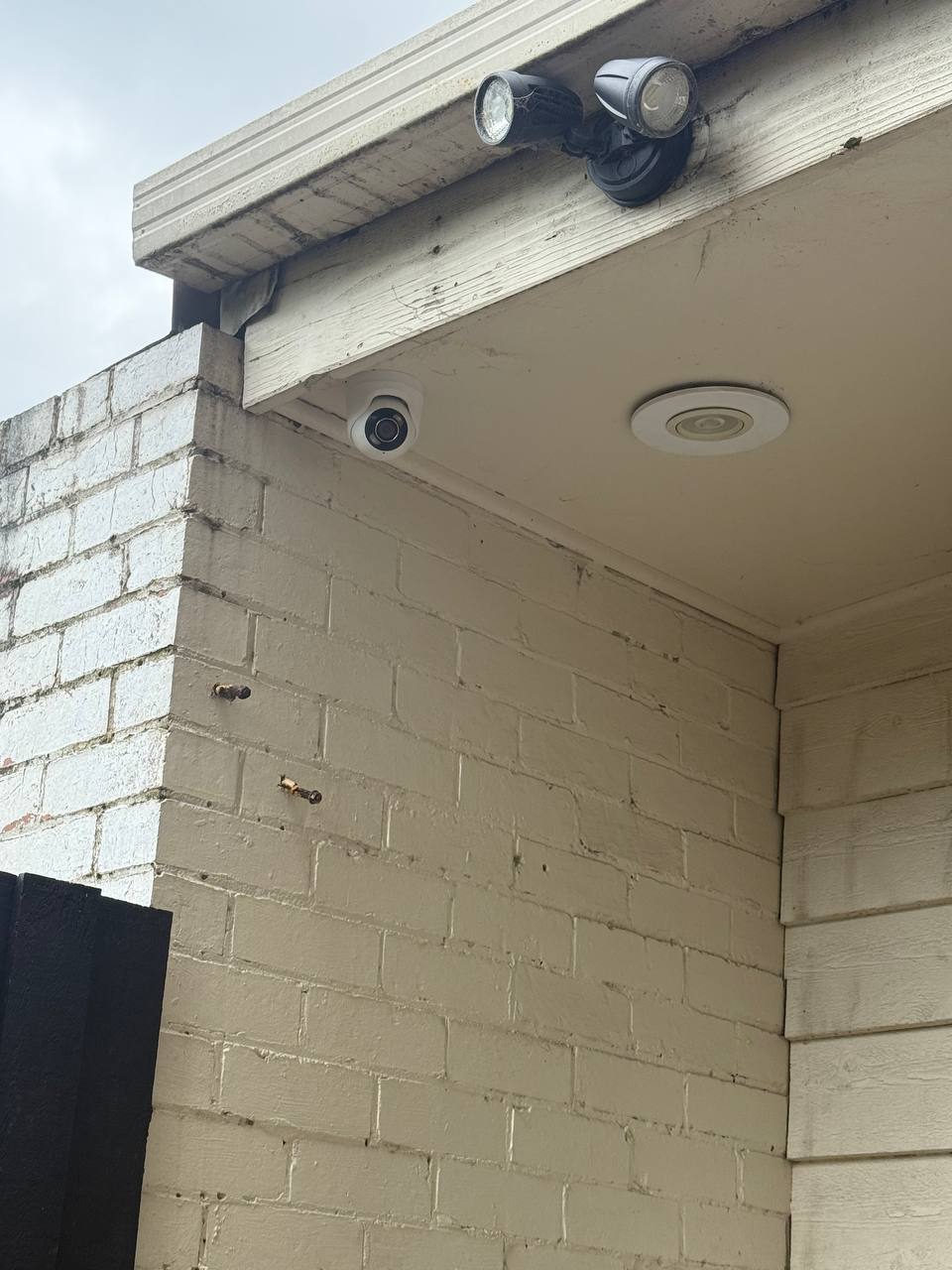 Outdoor AJAX siren and security camera mounted on a brick wall