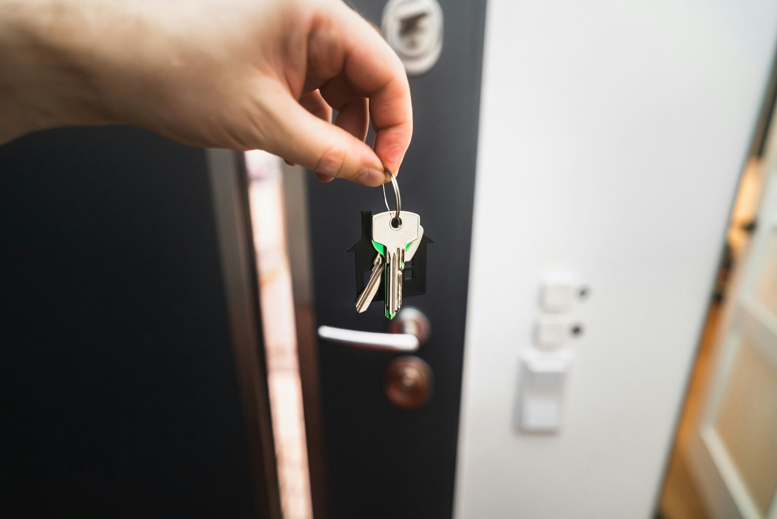 Hand holding a house key at the front door of a new home