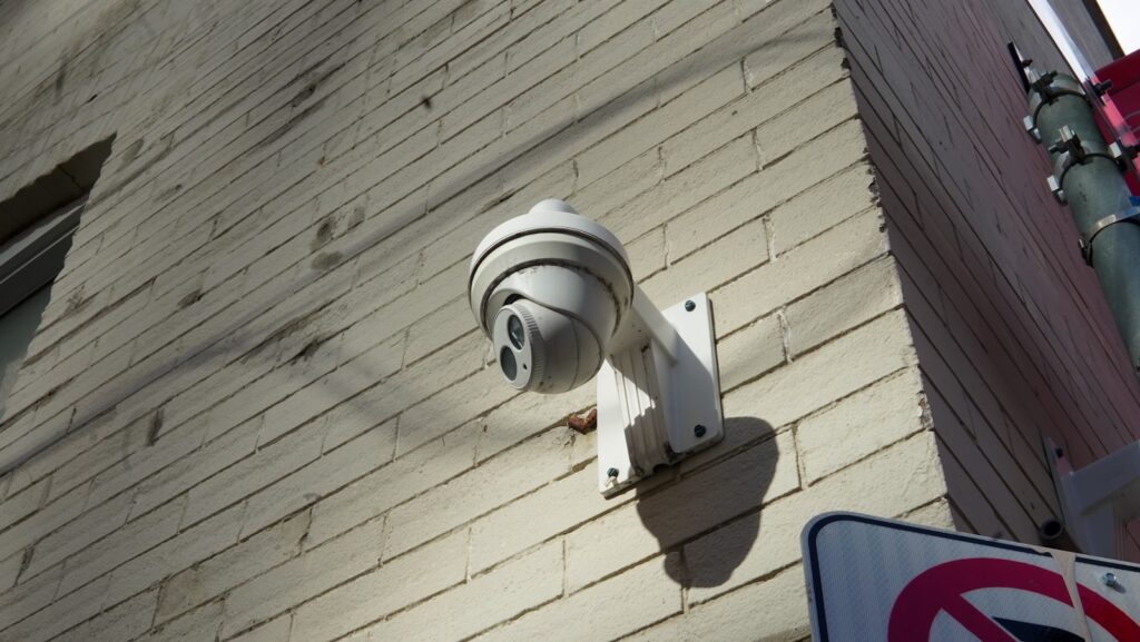 Turret-style security camera mounted on a brick wall at a commercial premises