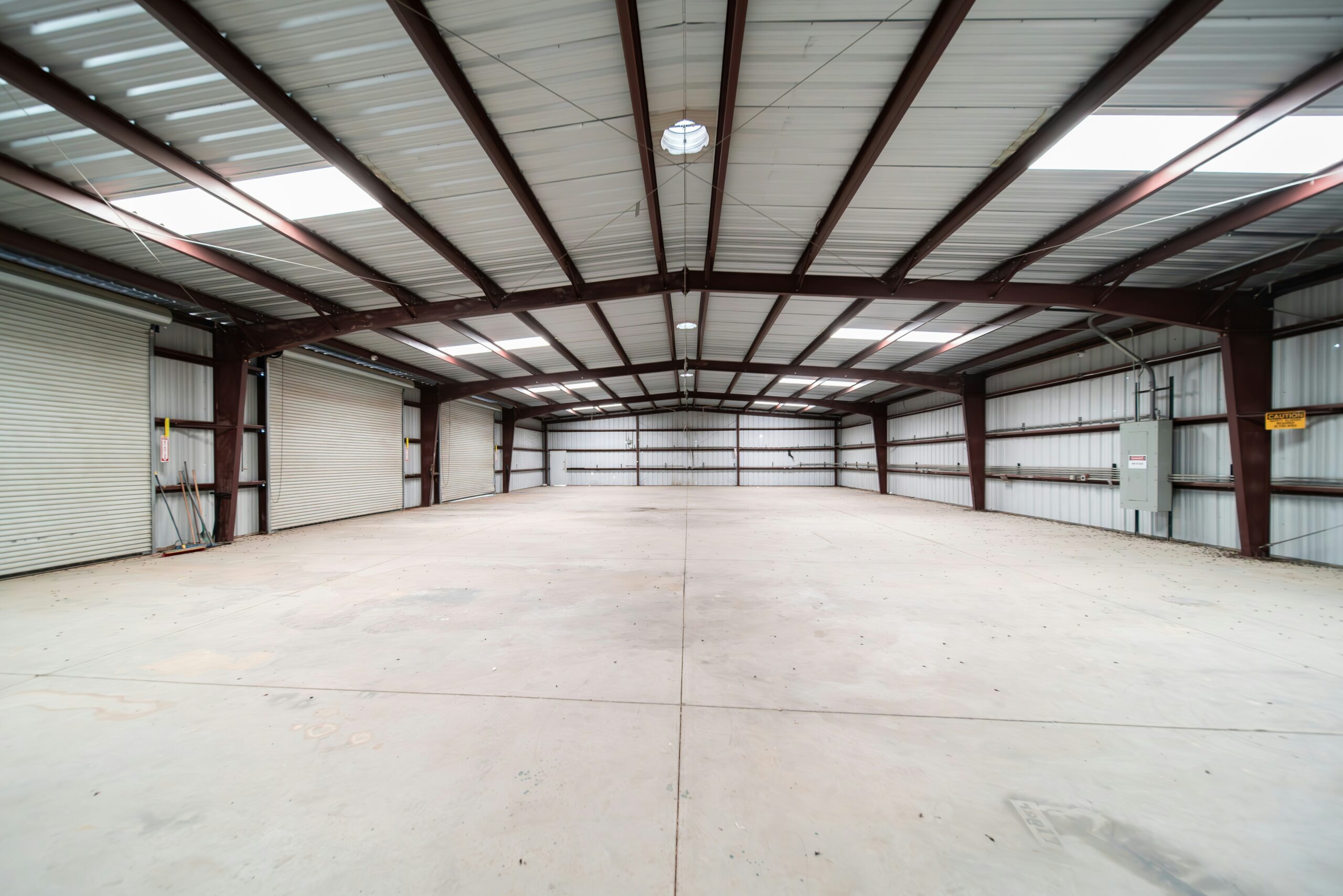existing-security-system-commercial-property-warehouse - SIPKO Security Empty commercial warehouse interior with steel roof trusses