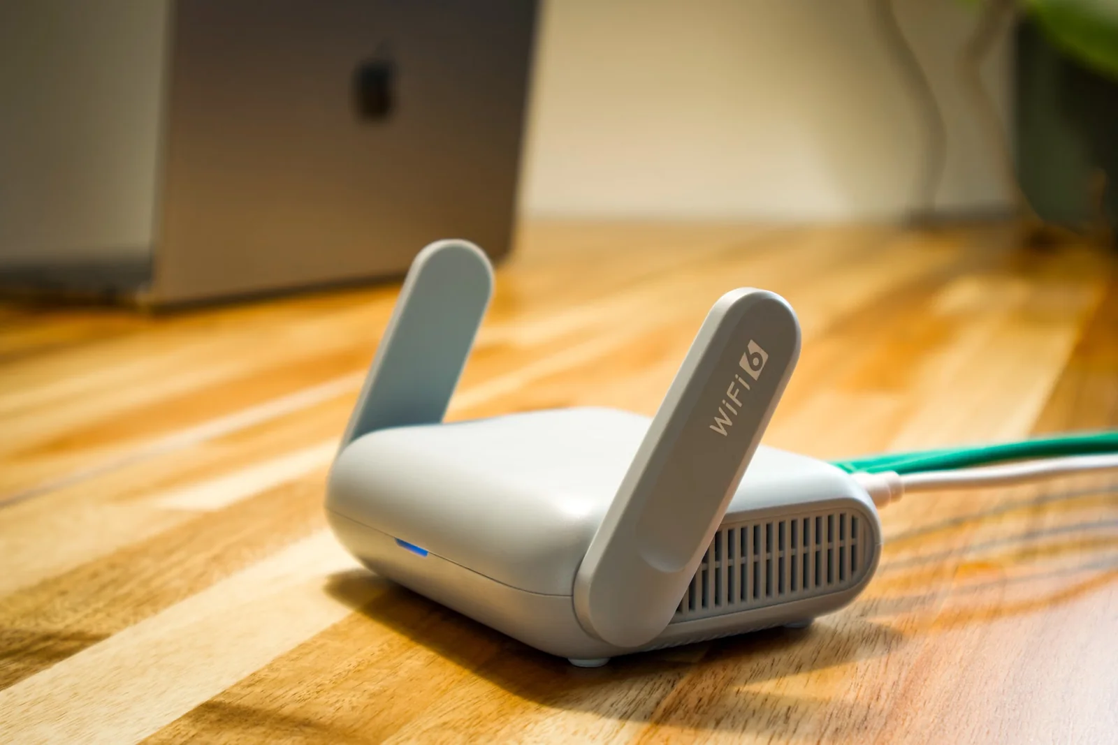 Wi-Fi router and network cable - SIPKO Security White Wi-Fi router with two antennas and a network cable on a wooden desk.