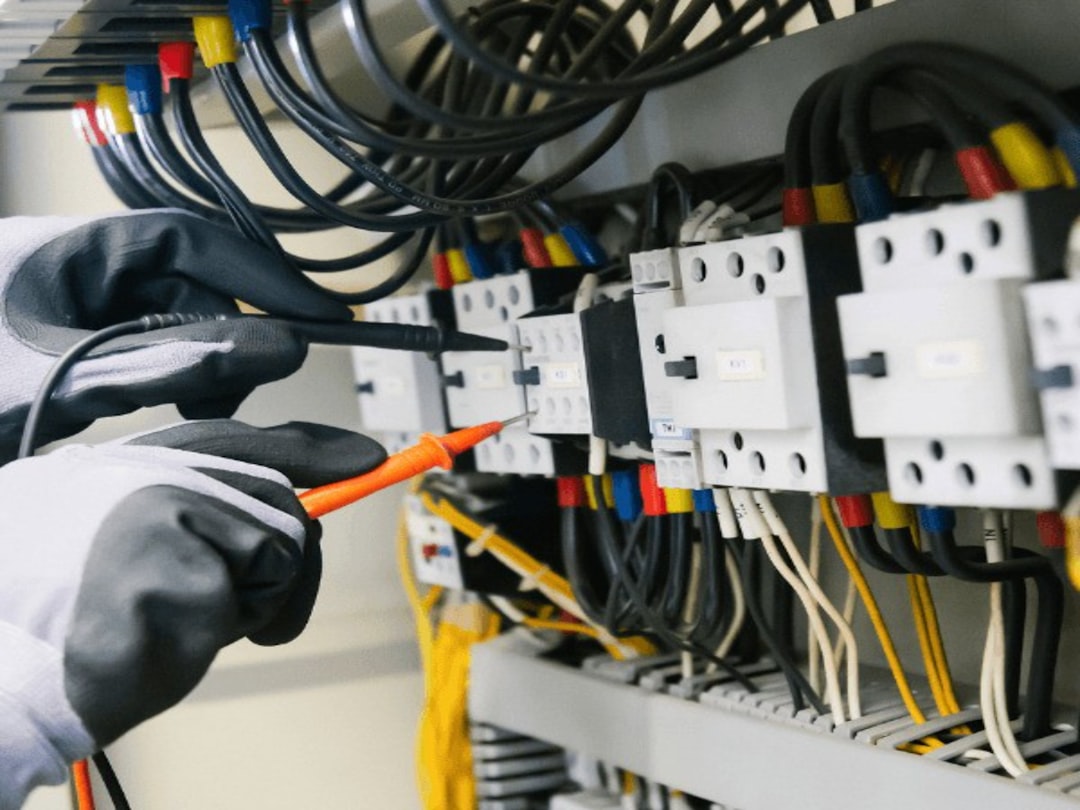Technician testing wiring and connections inside an alarm control panel