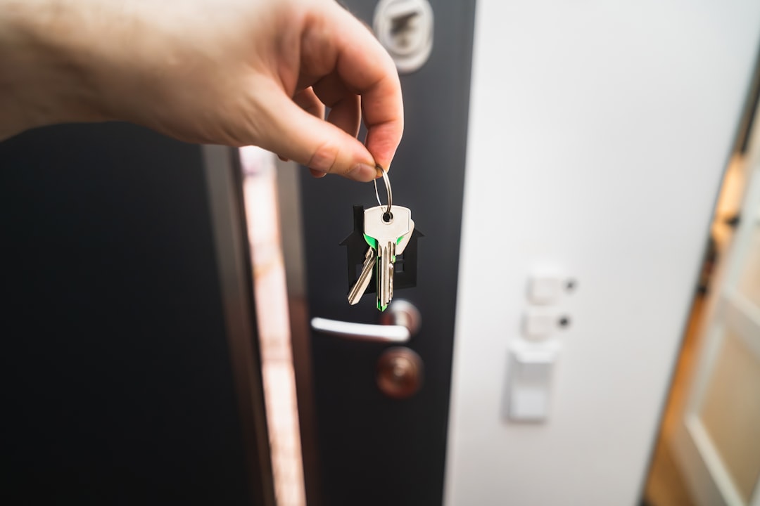 new-home-security-checklist-new-keys - SIPKO Security Holding a new set of house keys at the front door entrance of a home