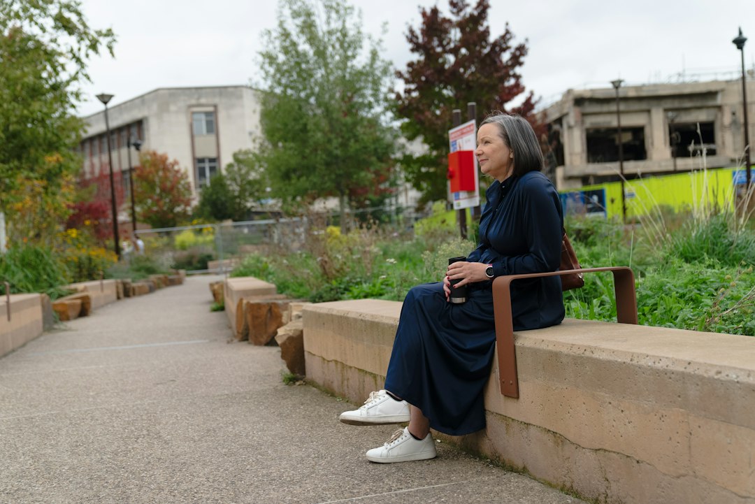 Senior woman sitting on a park bench outdoors, away from home