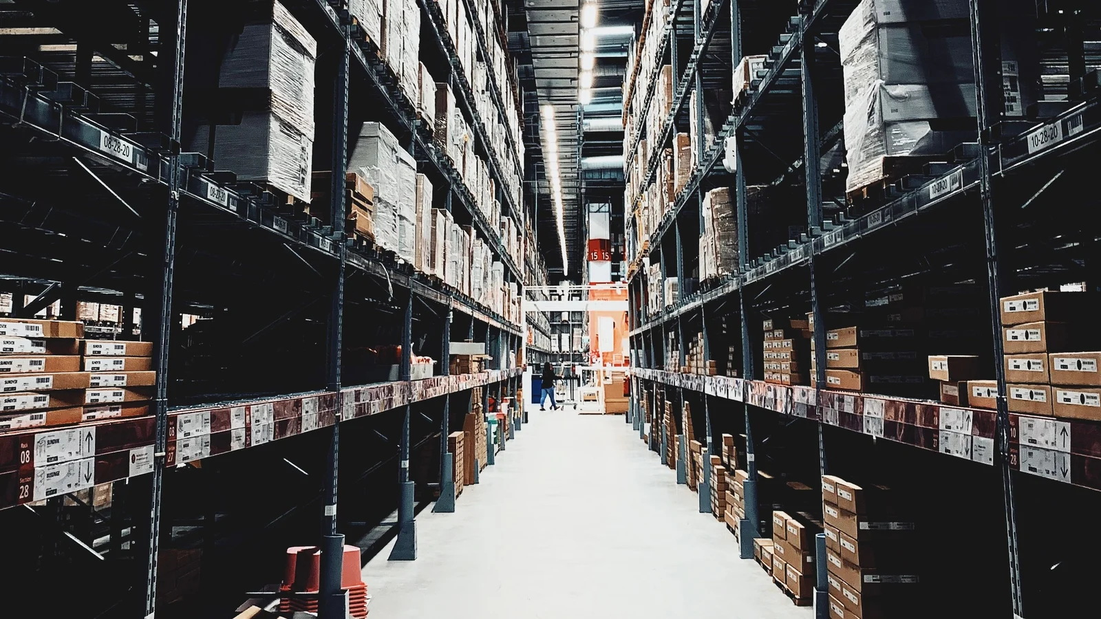 Warehouse aisle between tall storage racks stacked with boxes