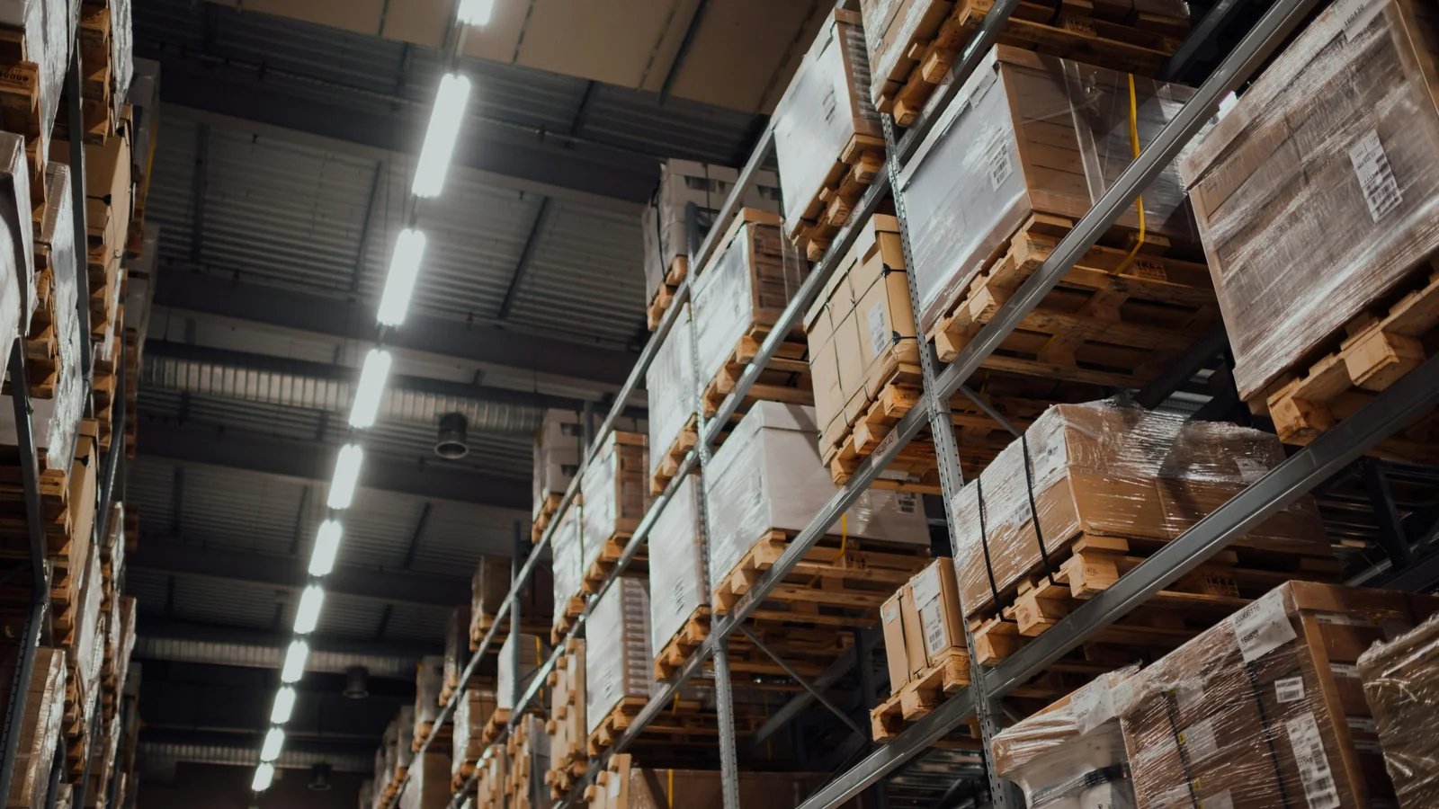 Warehouse storage racks and coverage planning - SIPKO Security Tall warehouse storage racks stacked with boxed goods on pallets