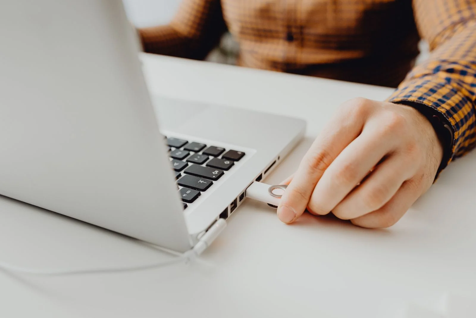 Hand connecting a USB flash drive to a laptop - SIPKO Security Hand connecting a USB flash drive to a laptop, the kind of check you make on an exported clip