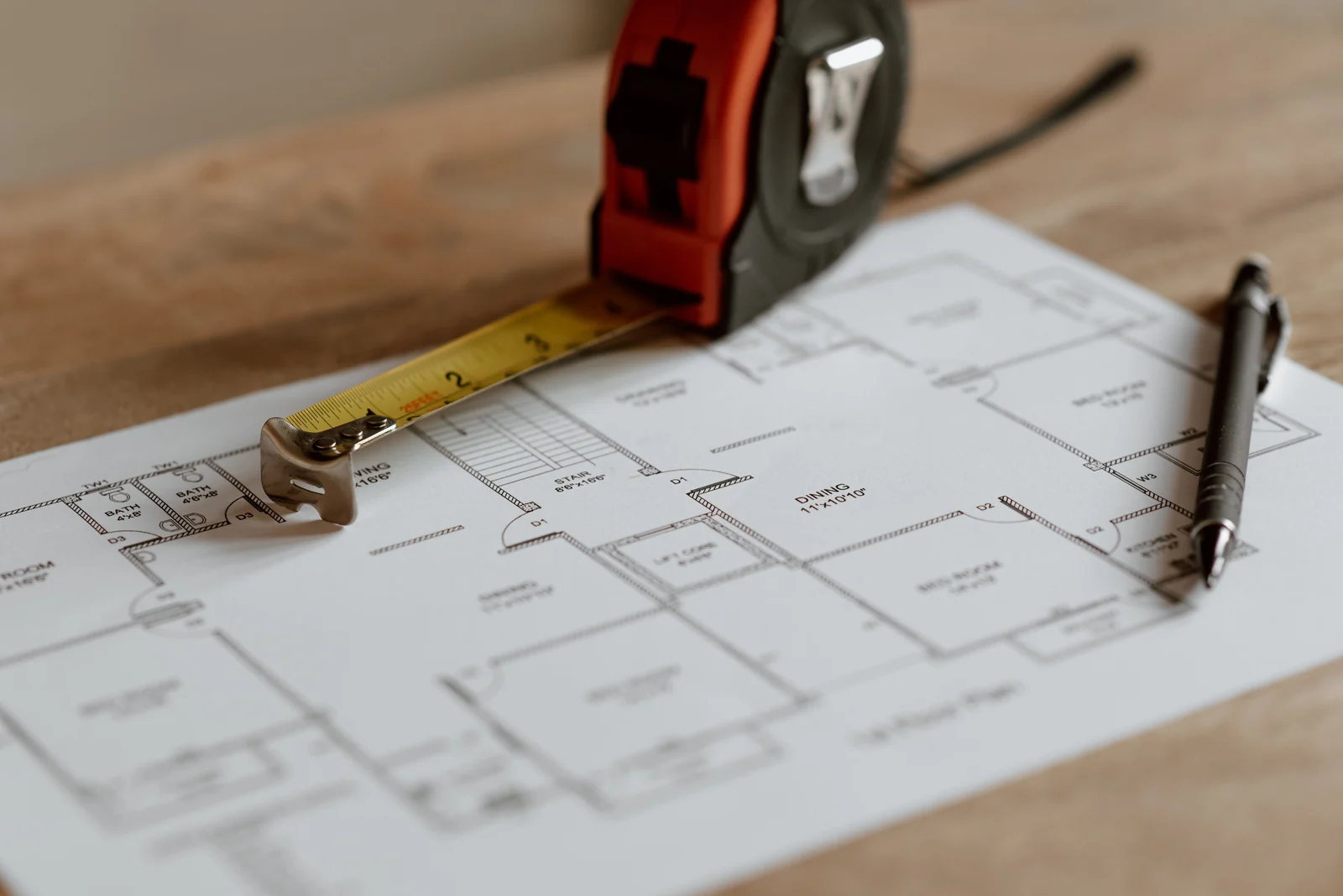 House floor plan and measuring tape - SIPKO Security House floor plan with a measuring tape and pen on a wooden table