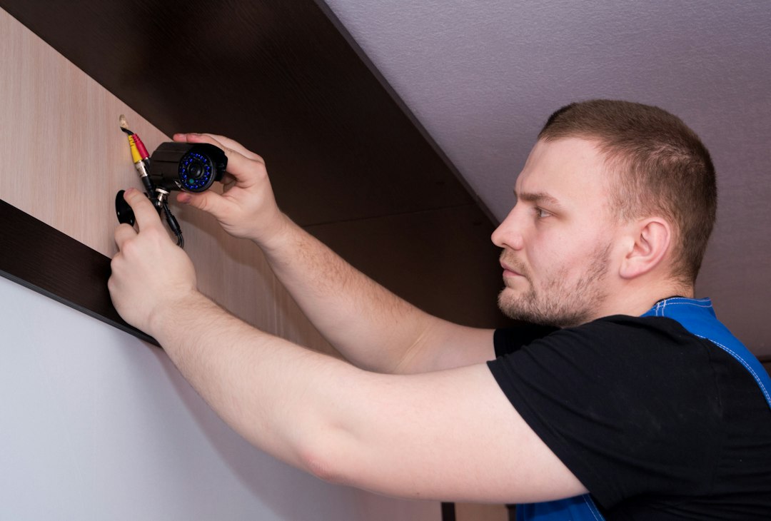 lower security alarm cost - installer on ladder - SIPKO Security Technician on a ladder fixing a security device to a wall