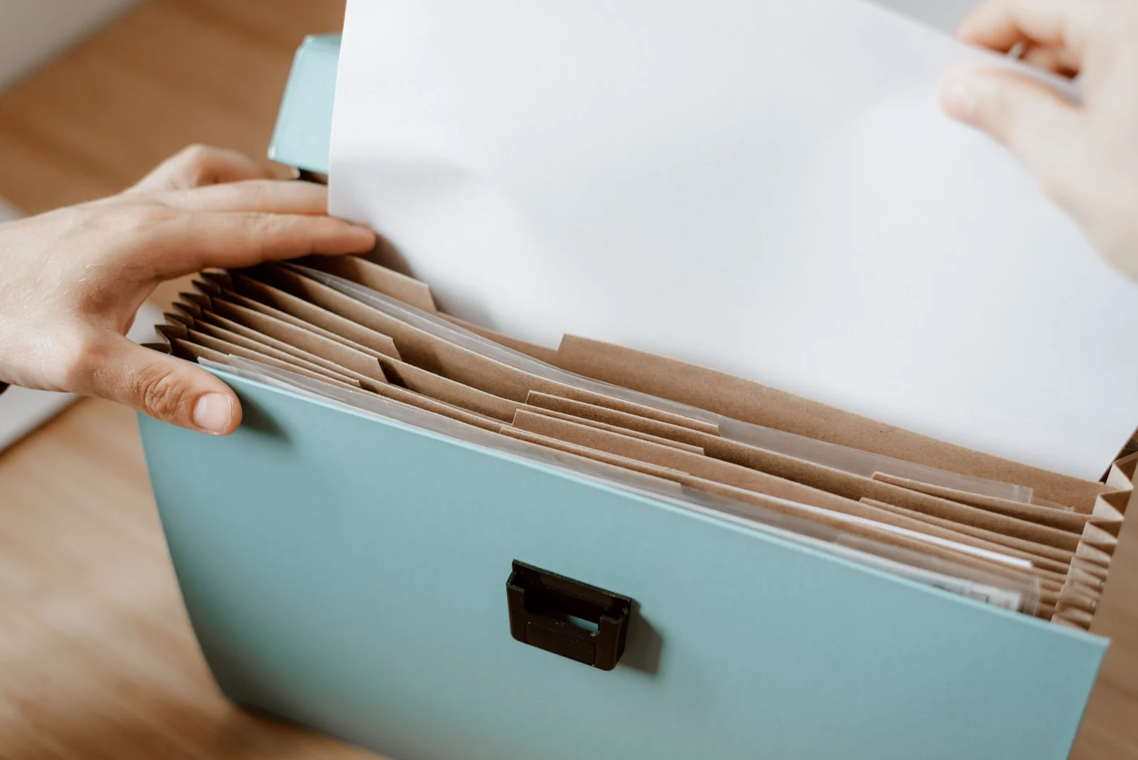 Organising home system records - SIPKO Security Hands taking a sheet of paper from a document folder of alarm records and manuals