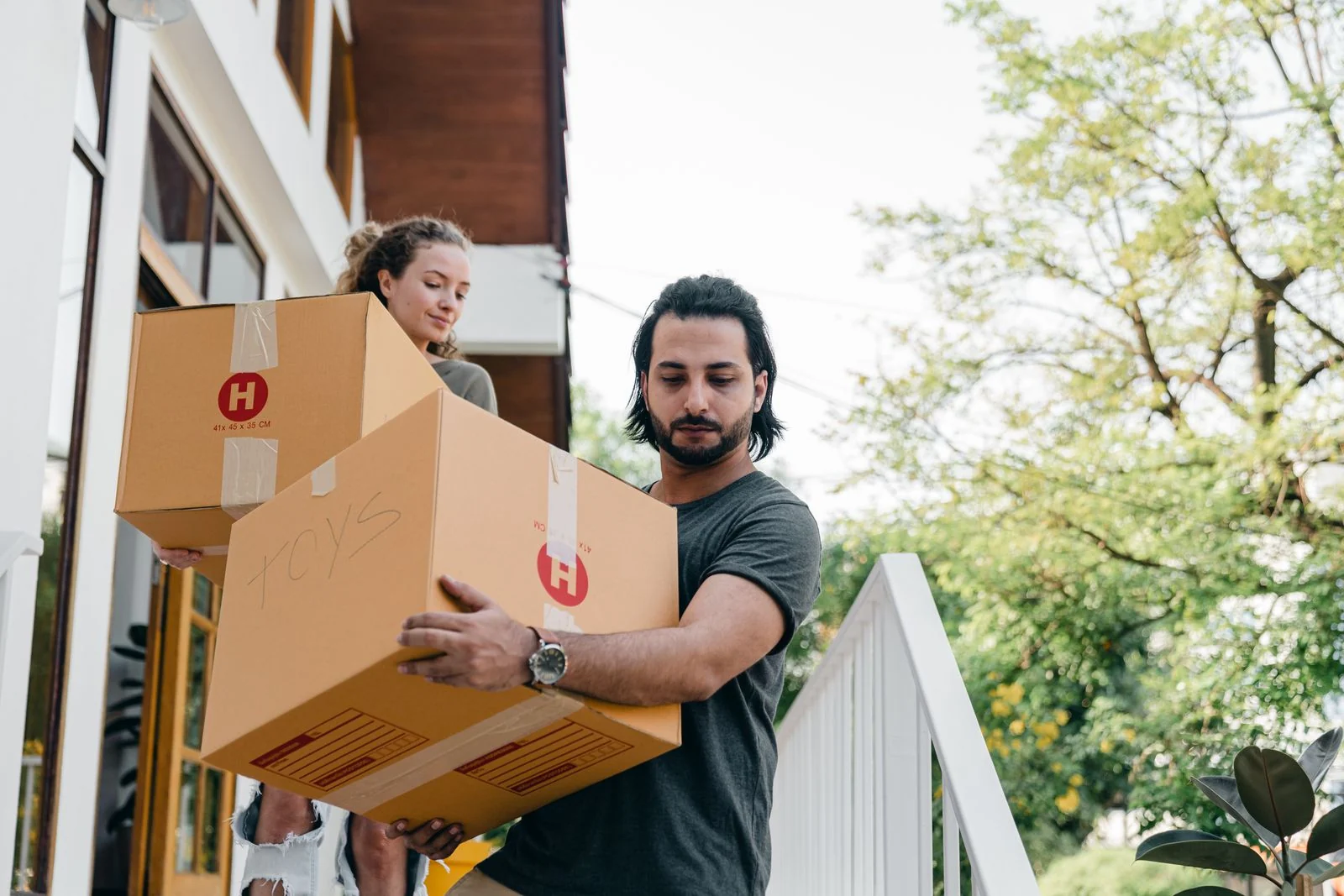 Renting guide - supporting photo 1 - SIPKO Security Couple carrying moving boxes down the steps of a home