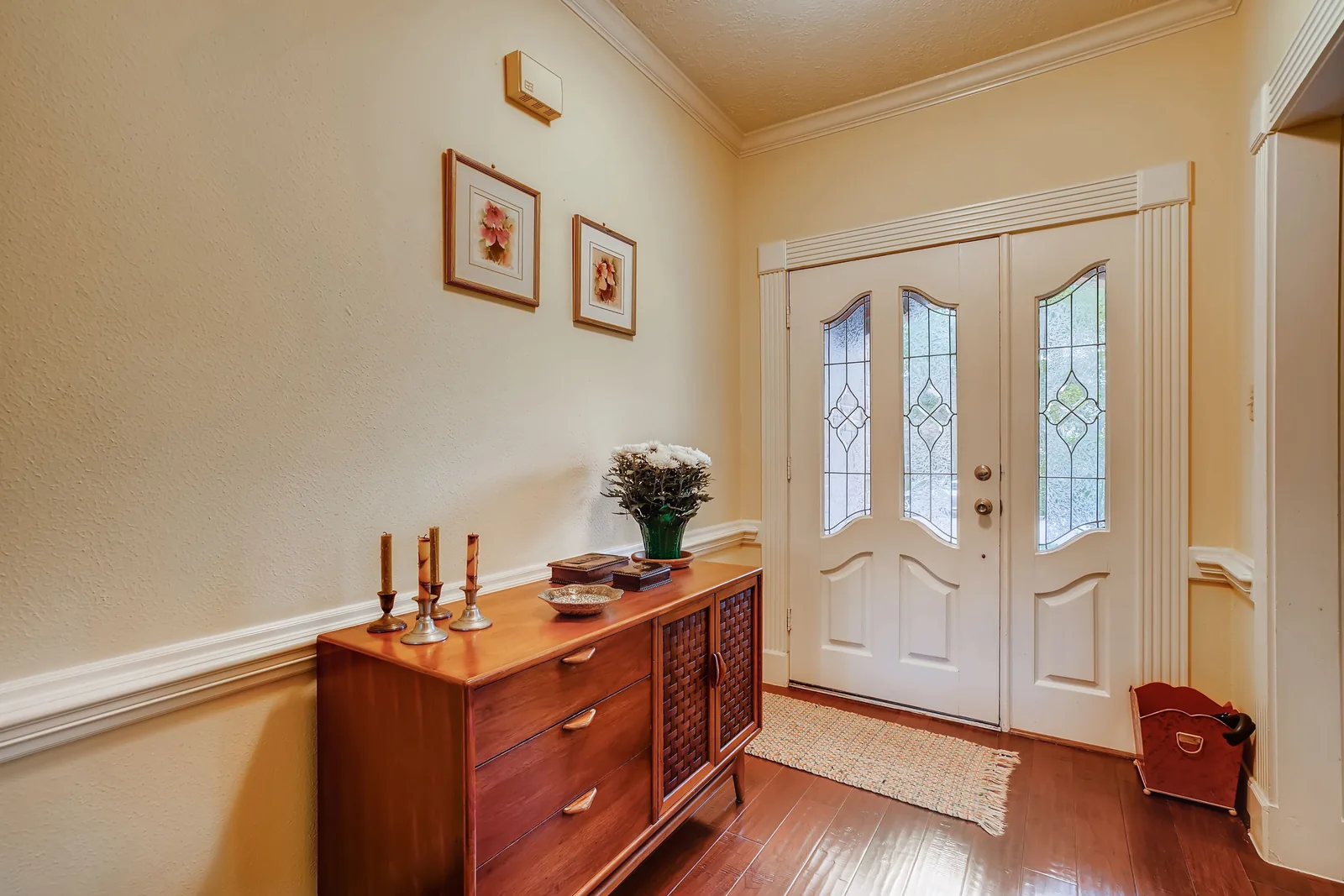 Residential front door and entryway - SIPKO Security White front door with decorative glass beside a wooden hallway sideboard