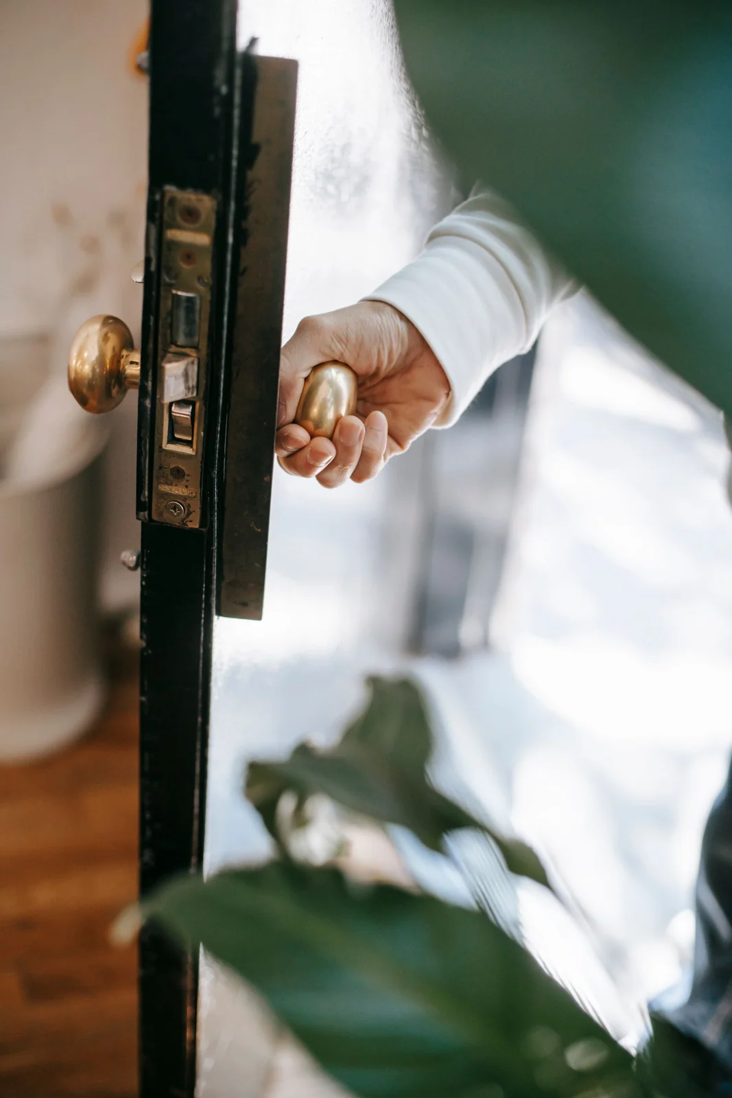 Hand opening a door with a brass handle