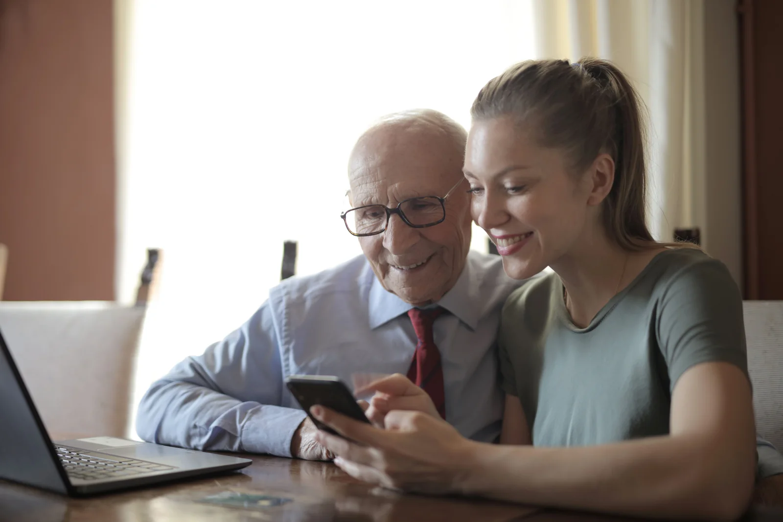 Young woman showing a smartphone to an older man at a table