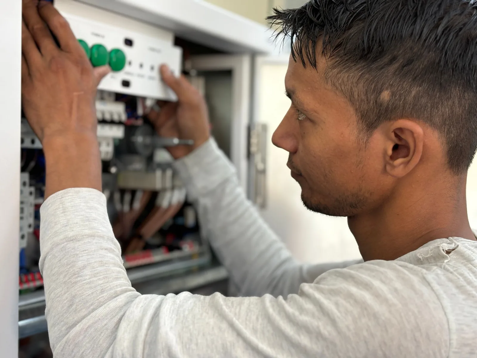 Technician inspecting an electrical control panel - SIPKO Security Technician mounting a wireless alarm hub and checking wiring during installation