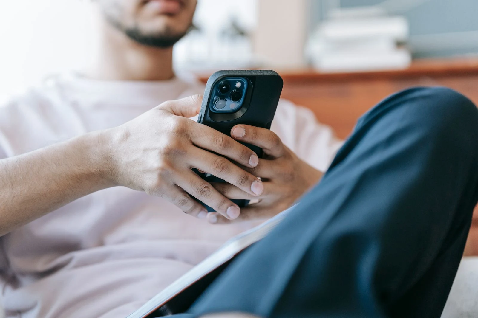 Man checking a smartphone while seated in a living room - SIPKO Security Man checking a smartphone while seated in a living room